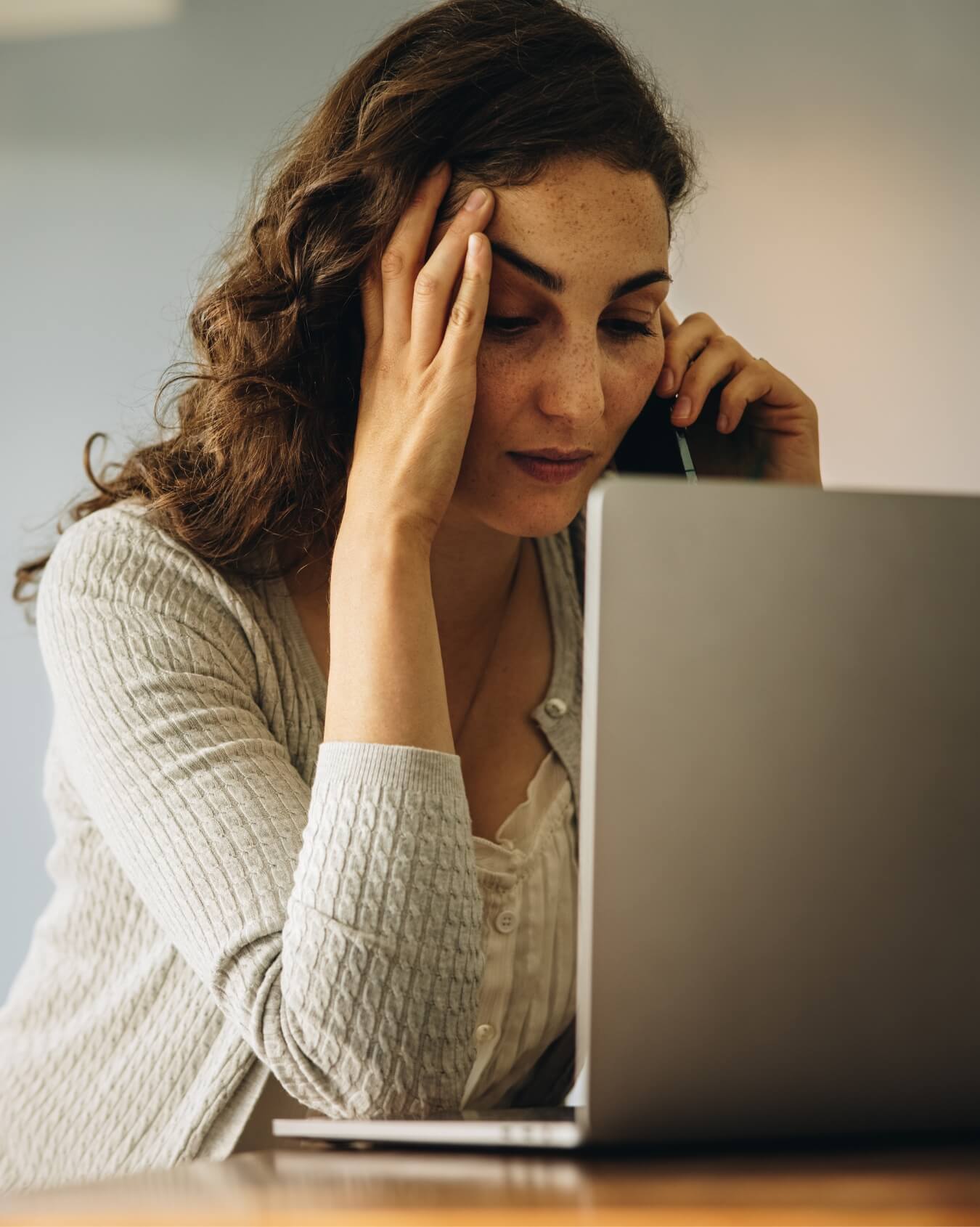 Mujer tocándose la frente y con expresión preocupada hablando por teléfono