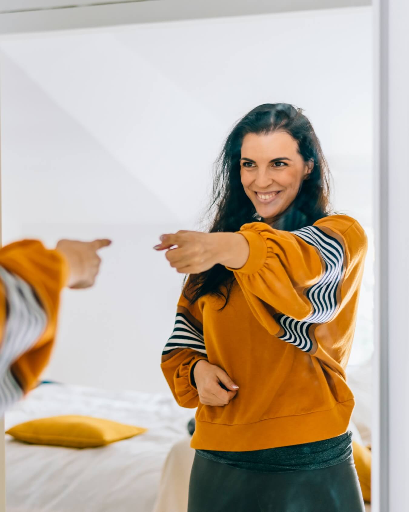 Mujer mirandose al espejo y señalando su reflejo
