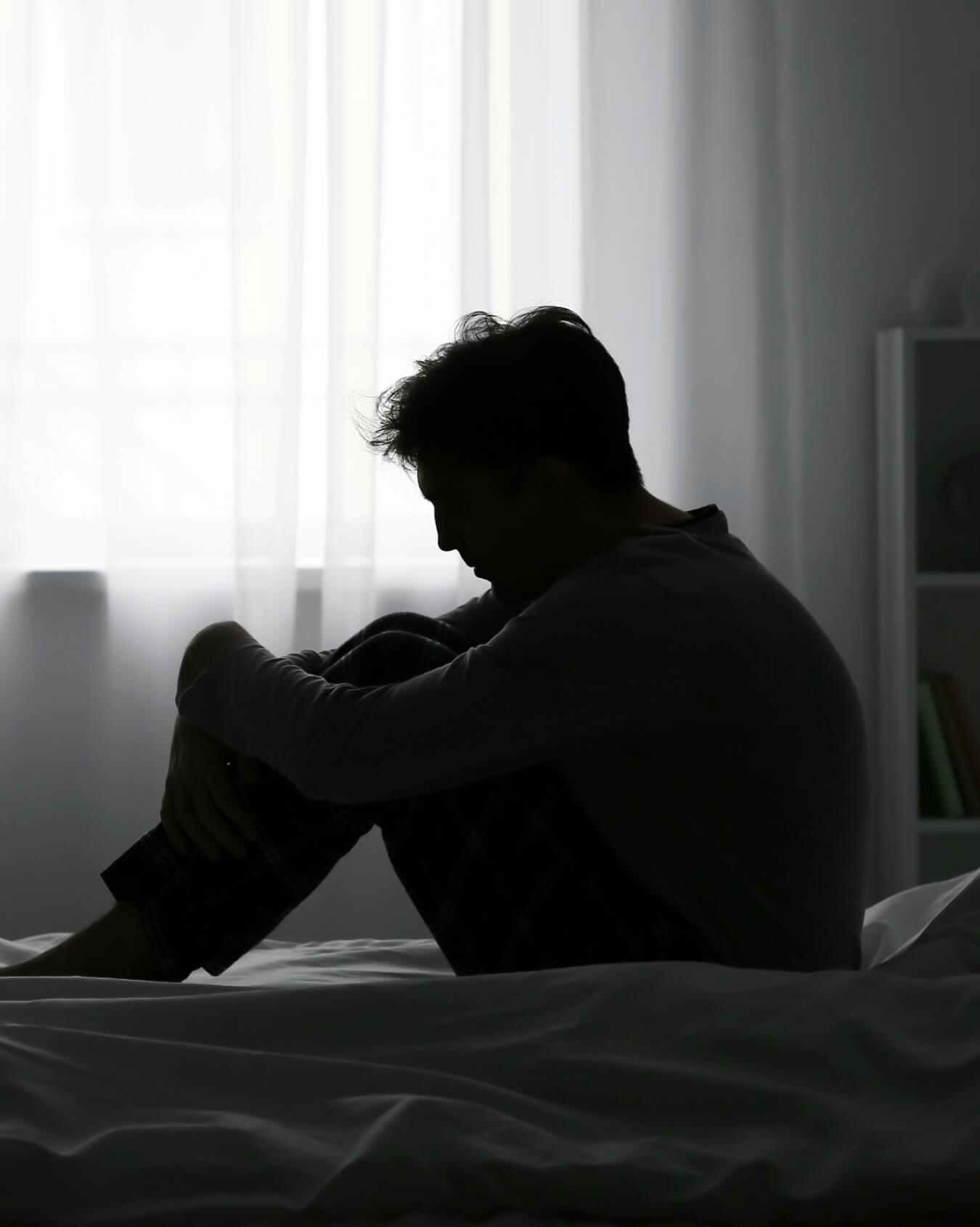 Hombre tumbado sobre la cama en penumbra